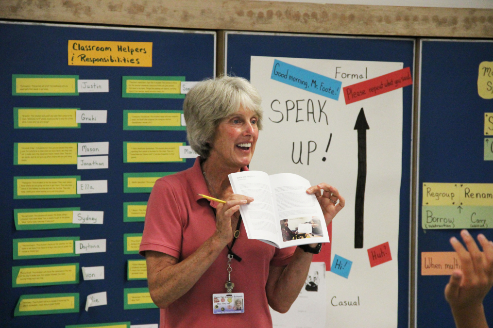 terry test holding a book open in front of a class
