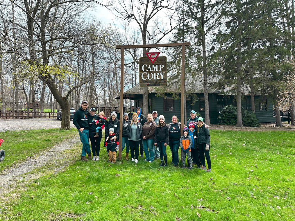 Volunteers working at Camp Cory pose together beneath camp sign